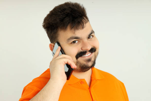 Fat man with a phone, close-up, on a gray background.