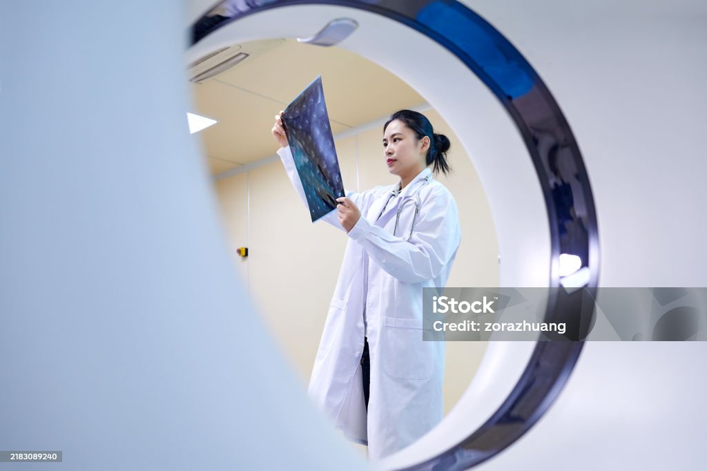 MRI 스캐너 룸에서 필름을 검사하는 여성 의사 - 로열티 프리 MRI 스캔 스톡 사진 MRI 스캐너 룸에서 필름을 검사하는 여성 의사 - 로열티 프리 MRI 스캔 스톡 사진