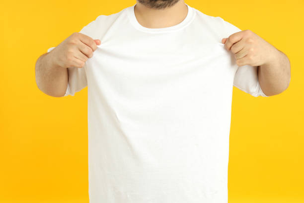 istock A man with a blank white t-shirt, on a yellow background. 2183089608