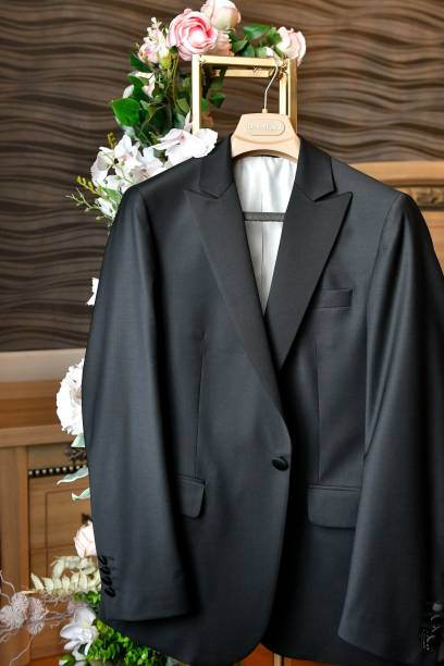 istock Elegant black suit jacket on a hanger with floral background 2183090329