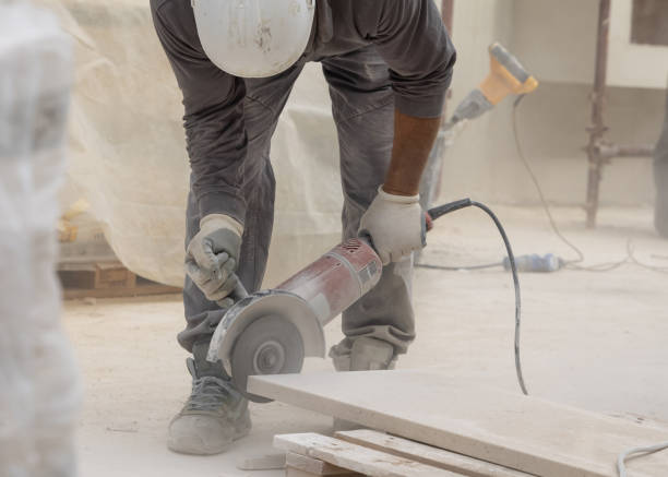 istock Craftsman in grey work clothes and helmet cutting marble piece during construction 2183091002