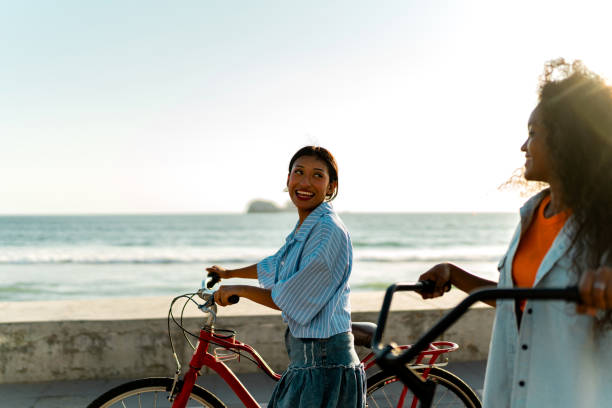istock Young female friends riding bicycles on coastline beach 2183091404