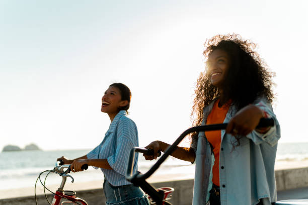 istock Young female friends riding bicycles on coastline beach 2183091433