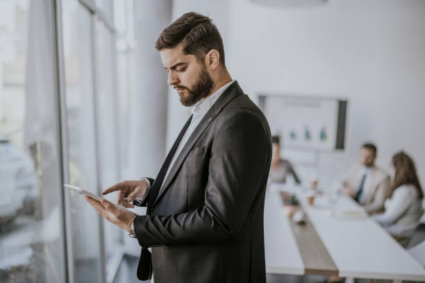 istock Businessman uses tablet while observing meeting in modern office 2183092135