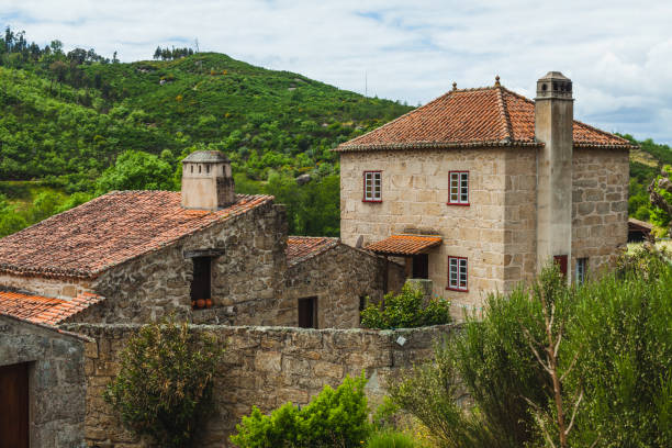 istock A charming rustic stone house with red-tiled roofs stands amidst lush green hills, exuding a tranquil rural atmosphere and traditional architectural style 2183101507