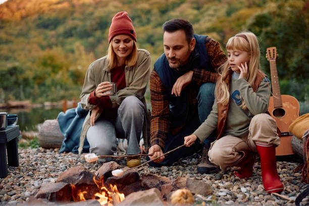 istock Smiling parents and their daughter roasting marshmallows over a campfire in nature. 2183101777