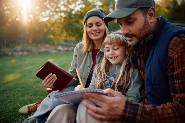 Happy little girl sketching in notebook while enjoying in nature during autumn