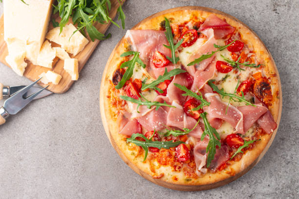 istock Pizza with prosciutto, ham, arugula, spinach, tomatoes, pesto, cheese and parmesan. Italian cuisine 2183102732