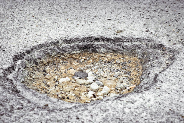 Close-up showing dirt and gravel below the asphalt surface of a street.