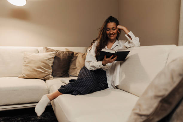 istock Woman reading book at home at night 2183106016