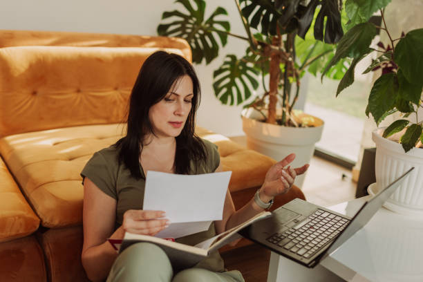 istock Woman Working Remotely with Laptop and Papers at Home 2183114310