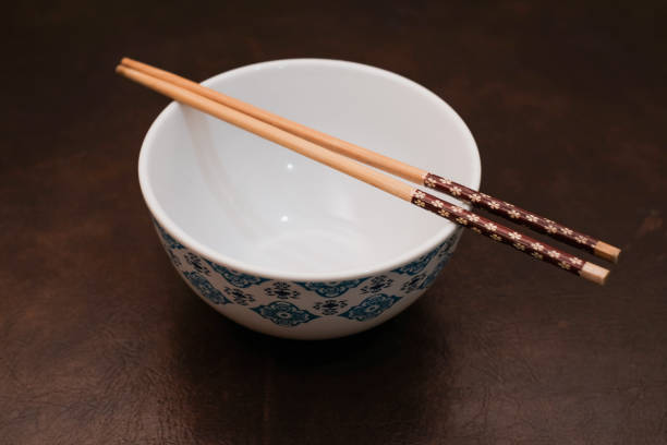 istock White bowl with blue pattern outside and wooden chopsticks on brown background 2183114542