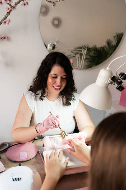 istock Manicurist using brush to clean dust of nails of a client 2183114815