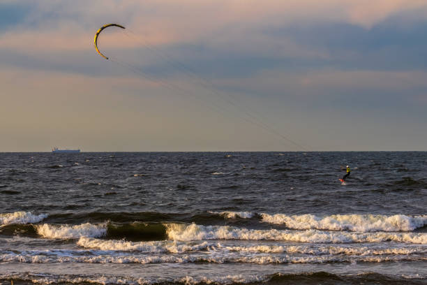 Muscular build man surfing on kiteboard during summer day at sea. Copy space.
