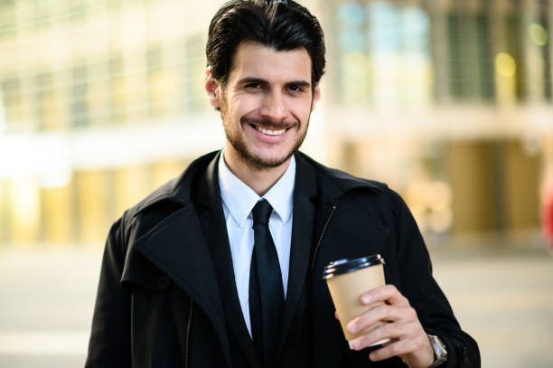 istock Smiling businessman holding coffee outside office building 2183118836