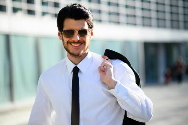 istock Smiling businessman wearing sunglasses holding jacket over shoulder 2183118847
