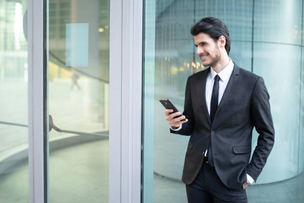 istock Businessman smiling and using mobile phone outside office 2183118998