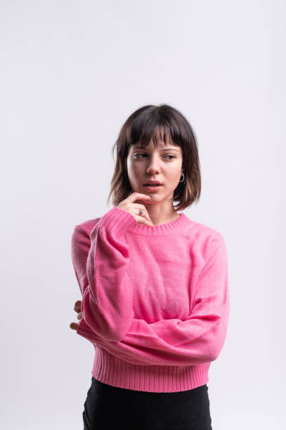 istock Young woman thinking and touching chin while wearing pink sweater 2183120695