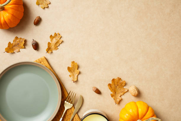 istock Autumn table setting with pumpkins, leaves, and cutlery on a beige background. Perfect for fall themes, Thanksgiving, and seasonal food presentations 2183124564