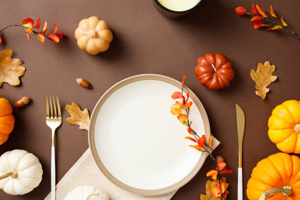 istock Thanksgiving table setting with autumn decorations. Featuring pumpkins, fall leaves, and an empty plate ready for a festive meal on a rich brown background 2183125053