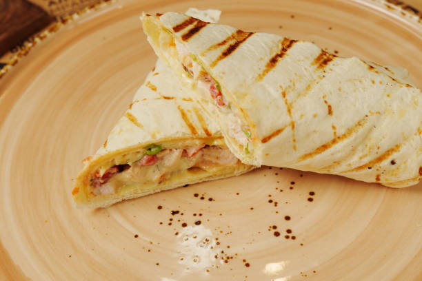 Roll with pita, meat, tomatoes, cheese, sauce, salt and spices on a white background