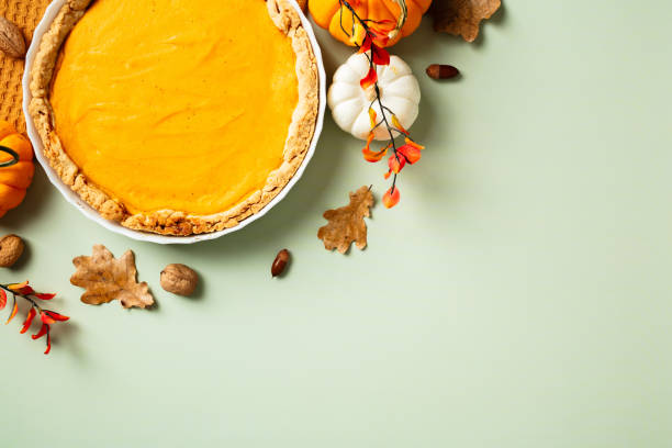 Delicious pumpkin pie with autumn decorations on a pastel green background. Perfect for Thanksgiving, fall celebrations, and seasonal cuisine themes