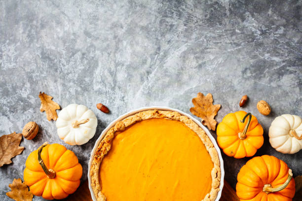 istock Pumpkin pie on dish with pumpkins, walnuts, oak leaves on stone background. Flat lay, top view 2183125835