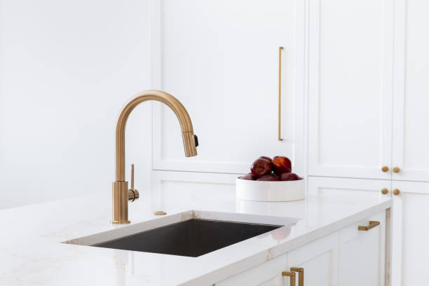 istock A gold faucet detail in a white kitchen. 2183125847
