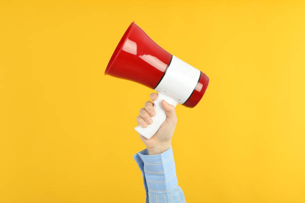 istock Female hand holds megaphone on yellow background 2183126035