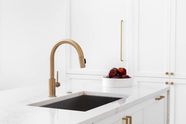 istock A gold faucet detail in a white kitchen. 2183129514