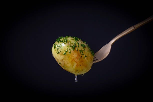 Fork with boiled young potato on a black background. Close up