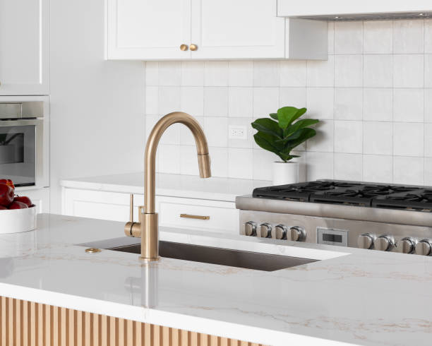 istock A gold faucet detail in a white kitchen. 2183133222