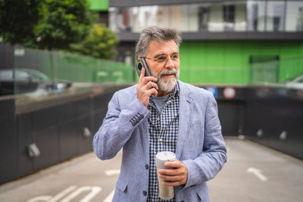 istock senior man talk on mobile phone on coffee break in front company 2183141681