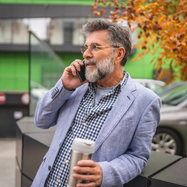 istock senior man talk on mobile phone on coffee break in front company 2183141683