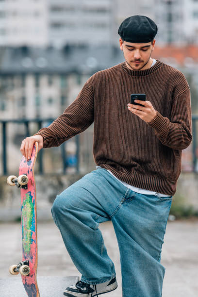 istock young man on the street with mobile phone and skateboard 2183141806