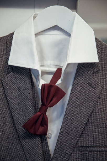 istock Elegant suit with a maroon bow tie hanging on a hanger in a stylish setting 2183143436