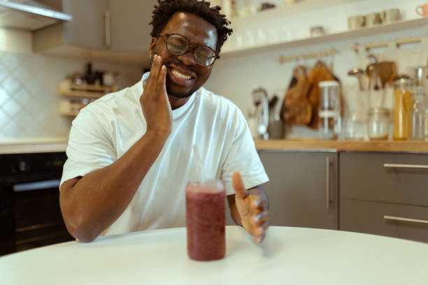 istock While sitting at the dining room table drinking a non-alcoholic smoothie in the kitchen, a black man experiences a severe toothache 2183147803