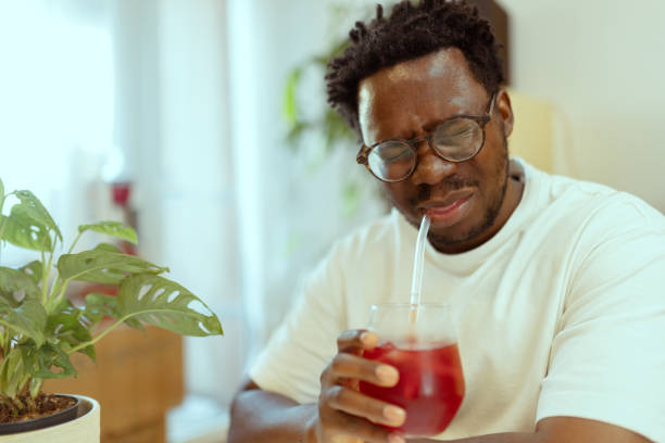 istock Portrait of a black man frowning while drinking cold, fruit juice with a straw due to sensitive teeth 2183147867