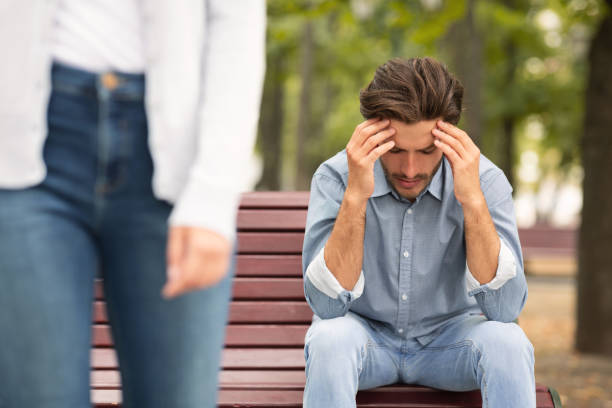 Young couple divorced and broke up relationship Young couple divorced and broke up relationship. Depressed man sitting on bench outdoor, his girlfriend leaving sad teenager boy crying outdoors in park stock pictures, royalty-free photos & images