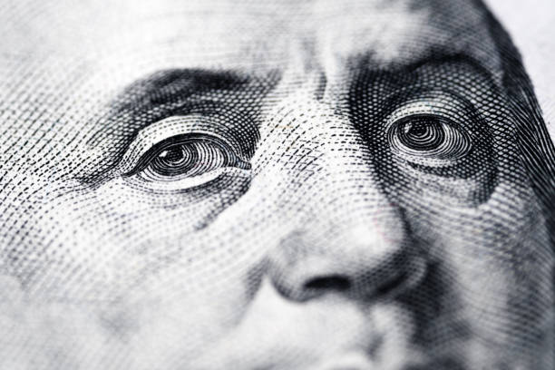 istock Close-up macro photograph with soft focus of Benjamin Franklin’s eyes on a U.S. one-hundred-dollar bill, detailed textures and intricate patterns of fine lines and dots. 2183149509