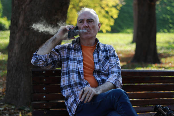 istock Senior man with vitiligo on head smoking in public park 2183156689