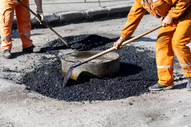 istock Workers use shovels to spread asphalt around a manhole cover 2183156758