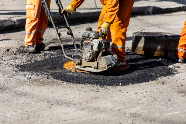 istock Workers repairing a road surface with asphalt in an urban area on a sunny day using a plate compactor to ensure proper leveling 2183156812