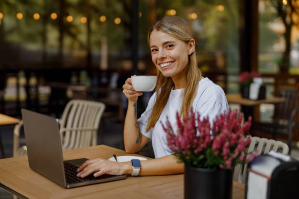istock Young Woman Enjoying Coffee While Working on Laptop at Caf 2183156932
