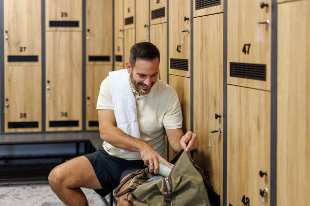 istock Man with towel on shoulder, finding items in gym bag 2183161875