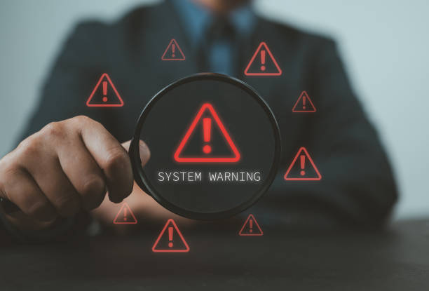 istock System Warning Alert, Cyber Security Concept. Hand holds magnifying glass over digital warning sign with red exclamation marks, system warning or potential malicious cyber attack alert. Cybersecurity, 2183166016