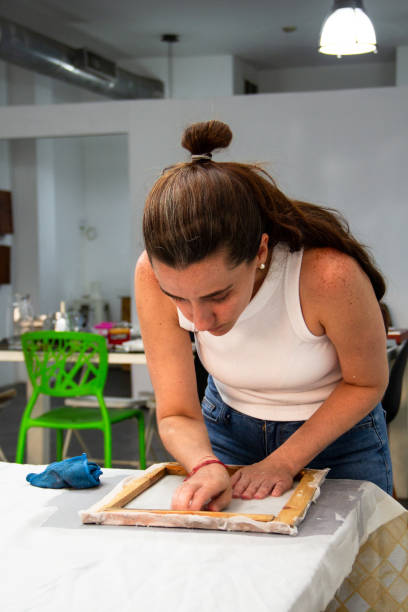 istock One woman using a deckle mold to make handmade recycled paper putting on a fabric sheet. Reusable and zero waste material concept. 2183170464