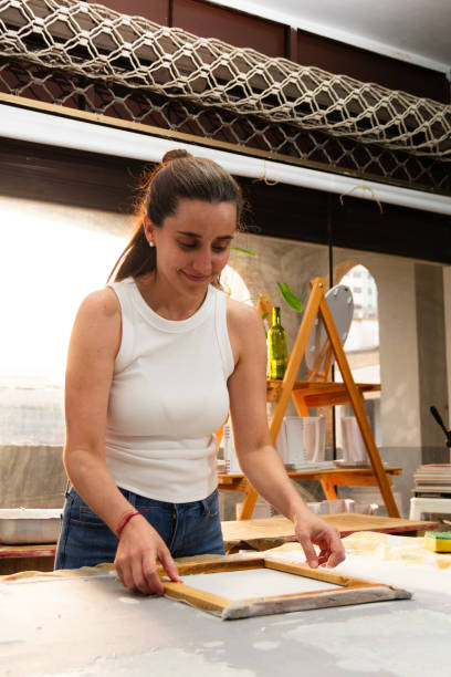 istock Creative artist engaged in the process of making recycled paper with deckle frame at a brightly lit studio during the afternoon hours 2183170999