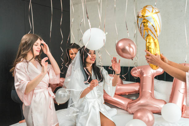 istock Hispanic Bride and Bridesmaids Play with Balloons on Bed at Bachelorette Prep 2183178968