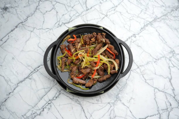istock Sizzling beef stir fry with vegetables on a frying pan, marble table background with copy space, close-up. Asian food menu 2183180147